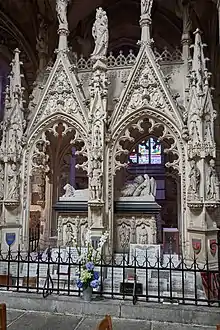 Photo représentant un tombeau monumental néogothique en pierre blanche, dans un bas-côté d'église