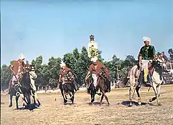 Photographie en couleur de cavaliers jouant à un jeu s'apparentant au polo