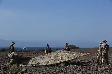 Des marines américains déploient un filet de camouflage, octobre 2014.