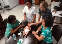 Un groupe de femmes médecins sont réunies autour d'une table sur laquelle est posée un mannequin