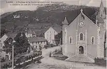Photo depuis une hauteur d'une pace de village avec le porche de l'église et un tramway.