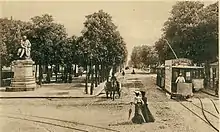 Carte postale en noir et blanc représentant une avenue sur laquelle circulent des tramways.