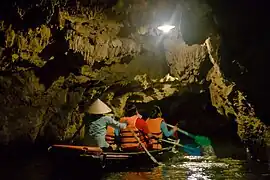 Barque touristique dans une grotte entre deux plans d'eau.
