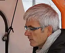 Portrait de profil dans un bateau. Cheveux blancs, lunettes.