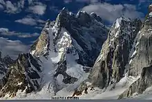 Silhouettes de marcheurs en file indienne devant une forte montagne.