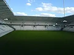 Vue intérieure d'un stade de football avec un terrain et de tribunes vides.