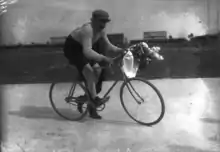 Photographie en noir et blanc d'un cycliste tenant un bouquet de fleurs dans les mains.