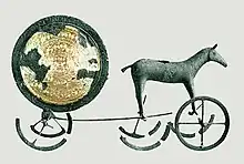 Artefact de bronze en forme de disque solaire sur roues, tracté par un cheval.