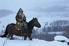 Photographie d'un homme à cheval dans la neige.