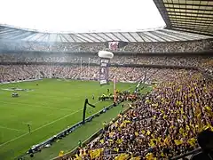 plan large d'un stade rempli de supporters aux couleurs noires et jaunes.