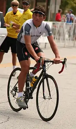 Homme blanc en tenue de cycliste pédalant sur un vélo.
