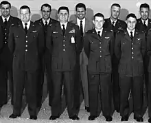 Neuf hommes en tenue militaire, souriants, face à la caméra.