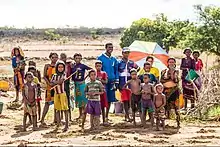 Photographie couleur d'un groupe de Malgaches comprenant des enfants devant un paysage aride.