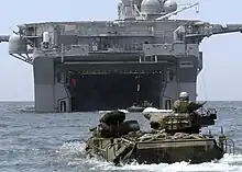 Un véhicule amphibie AAV-7 devant le radier inondable de poupe de l'USS Bonhomme Richard, s'apprêtant à enradier.