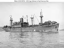 Photo de profil en noir et blanc du navire USS Cape Johnson naviguant dans la baie de San Francisco.