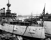 Photo en noir et blanc de l'avant d'un navire rempli de marins en uniformes de cérémonie.