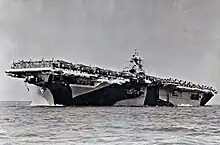 Photographie d'époque de l'USS Essex, un porte-avions bariolé de motifs géométriques noirs et blancs.