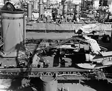 Photo de plusieurs navires alignés dans un chantier naval. On voit l'Indianapolis avec un avion sur sa catapulte.