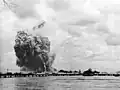 Le USS Mount Hood explose : les traînées de fumée sont laissées par les fragments éjectés par l'explosion.