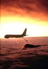 Photo d'un B-2 en train de se ravitailler derrière un KC-135, dans le Soleil couchant.