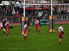 Les joueurs rouges sont rassemblés dans la zone d'en-but, devant une caméra fixe.