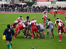 Des joueurs de rugby se regroupent pour former un maul autour du ballon.