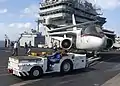 Tracteur de pont d'envol de l'US Navy en action avec un Lockheed S-3 Viking.