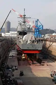 Le croiseur USS Cowpens (CG-63) (en) de la classe Ticonderoga en cale sèche dans la base navale de Yokosuka en mars 2004.