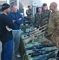 Des militaires autour d'une table sur laquelle est posée plusieurs armes.