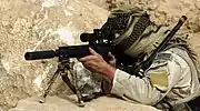 Un sniper américain regardant au travers une lunette d'un Mk12 Mod 1 SPR.