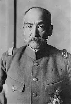 Photo en noir et blanc d'un homme asiatique en uniforme portant la moustache.