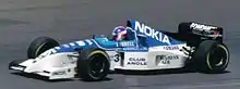 Photographie d'une monoplace de Formule 1, de couleur blanche et bleue, lors d'une course.