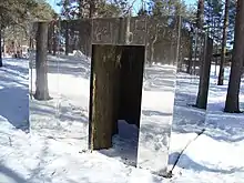 Mirrored structure in the form or a small dwelling, set in a forest.