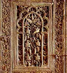 Photographie d'un panneau sculpté du minbar. Orné de motifs floraux et de pommes de pin, il a la forme d'une niche à fond plat.