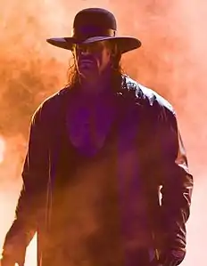 Photographie du catcheur (The) Undertaker. Des flammes (engins pyrotechniques) sont visibles en arrière-plan.