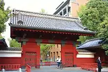 Photo couleur de la porte d'entrée rouge et du mur d'enceinte rouge et blanc de l'université de Tokyo.