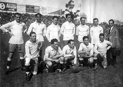 Photo d'avant match d'une équipe composée de onze joueurs de football habillés en blanc et de leur entraineur.