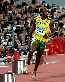 Usain Bolt courant en bord de piste, sous les objectifs des photographes.