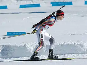 Une biathlète qui fait du ski de fond, sa carabine sur le dos.