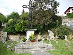 Vue d’une croix de cimetière entourée de stèles discoïdales.