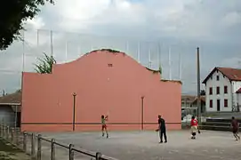 Photographie d'une partie de pelote basque rassemblant quatre joueurs utilisant une pala.