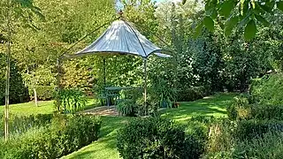 Jardin structuré de carrés de buis orné d'une tonnelle.