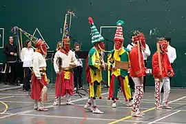 Photographie de six carnavaliers costumés à l’identique deux par deux, et dont quatre portent de hauts chapeaux pointus.