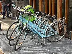 Plusieurs vélos bleus devant la Vélostation.