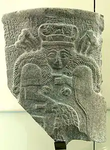 Fragment de vase en pierre sombre représentant une femme aux longs cheveux tressés.