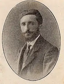 Portrait d'un homme barbu portant un costume et une cravate.