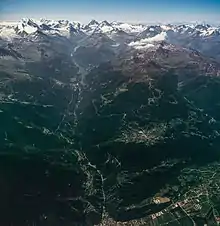 Vue d'avion d'une large vallée et de montagnes enneigées.