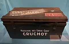 Cantine en métal de couleur noire avec les inscriptions « Maréchal des logis-chef Cruchot », « Congrès international de la gendarmerie » et « New York ».