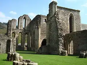 Nef d'église ruinée donnant sur un chœur dont reste le chevet, ainsi qu'un bras du transept.