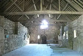 Photographie d'une vaste salle en pierre et recouvert d'une charpente de vastes dimensions.